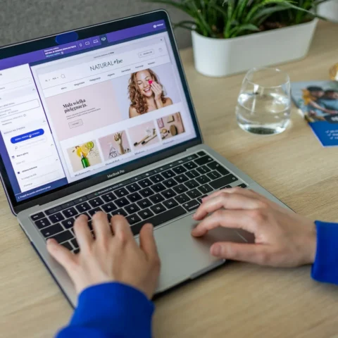 Händer på en laptop där en webbutik med produktbilder redigeras i butikens adminpanel