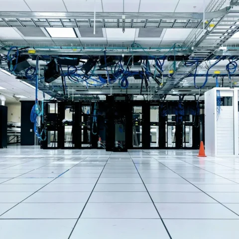 Ljus datahall med rader av serverrack och kabelstegar i taket