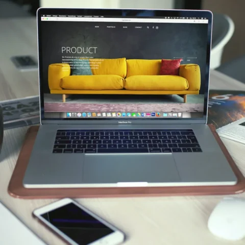 Laptop på ett skrivbord som visar produktsidan för en gul soffa i en webbutik